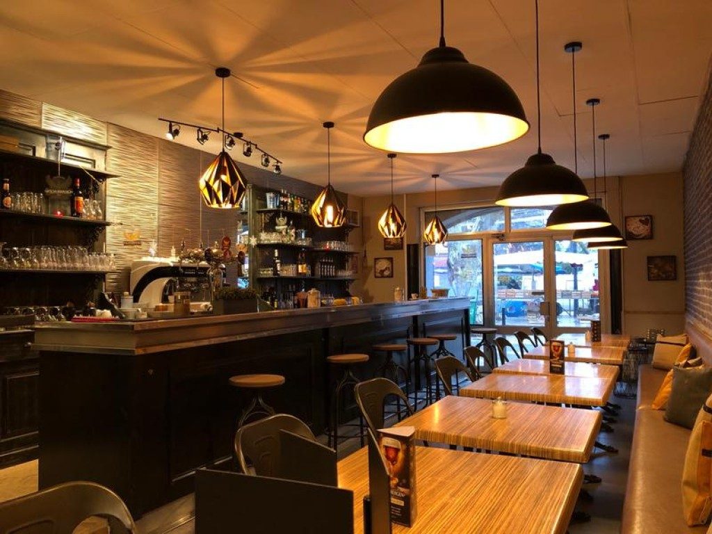 Le bar et ses suspensions en métal, devant les tables du restaurant
